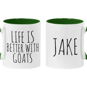 May include: Two white ceramic coffee mugs with green rims and handles. One mug says "Life is better with goats" and the other mug says "Jake".