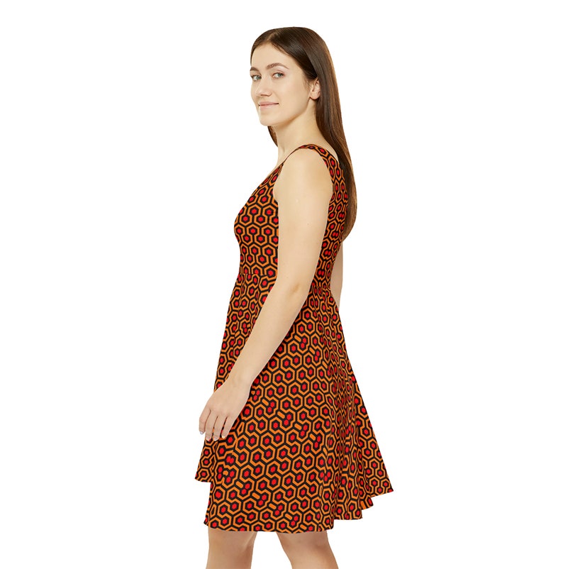 May include: A sleeveless dress featuring a repeating geometric pattern of orange and red hexagons outlined in black. The garment has a fitted bodice and a flared skirt that falls above the knee, showcasing a consistent print throughout the fabric.