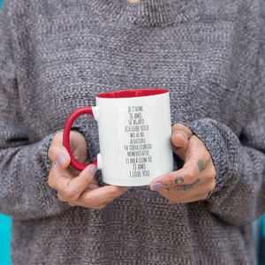 May include: White ceramic mug with a red rim and handle. The mug has black text that reads "Je t'aime, Te amo, Se agapo, Ich liebe dich, Wo ai ni, Aishiteru, Ya tebya liubliu, Nemehotatse, Is brea liom tu, Ti amo, I love you".