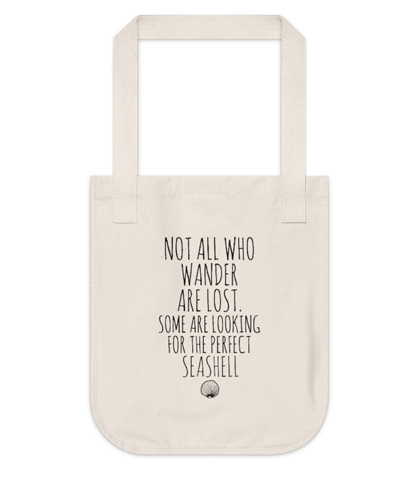 May include: A white canvas tote bag with black text that reads "Not all who wander are lost. Some are looking for the perfect seashell."  A small seashell graphic is below the text.