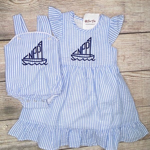 May include: A blue and white striped dress and matching onesie with a sailboat and the letters "NPP" embroidered on the front.