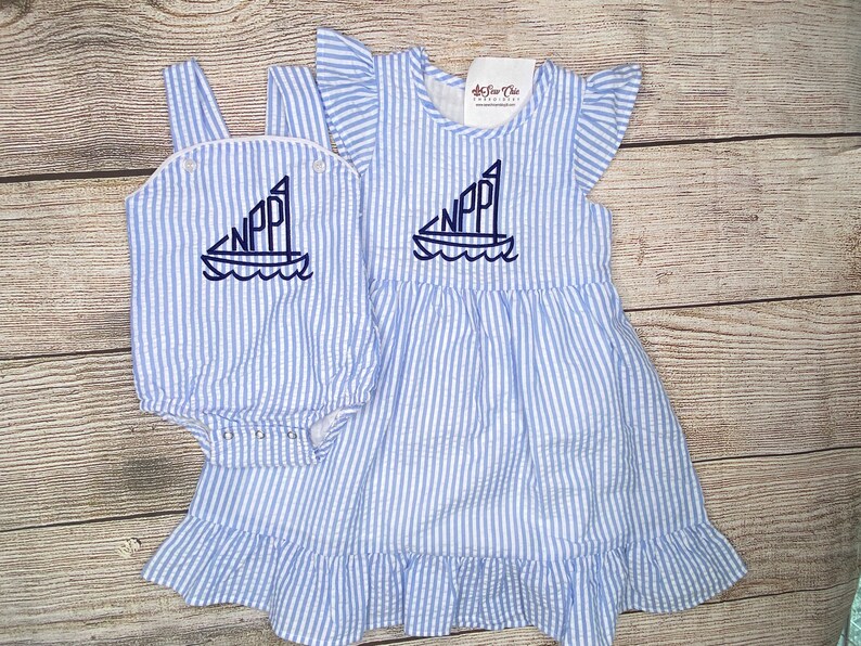 May include: A blue and white striped dress and matching onesie with a sailboat and the letters "NPP" embroidered on the front.
