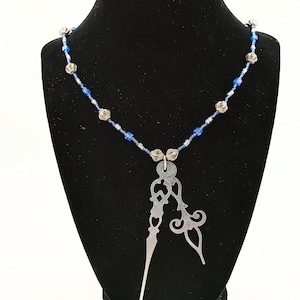 Peut inclure: Un collier en argent avec une chaîne de perles bleues et argentées et un grand pendentif en argent avec un motif de filigrane.