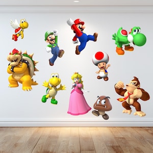 May include: A selection of vibrant cartoon character decals, including Mario, Luigi, Yoshi, and Princess Peach, are displayed against a white wall. Other characters include Bowser, Toad, Goomba, Donkey Kong, and Koopa Troopa. The characters are in various action poses.