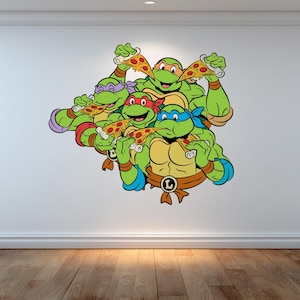 Puede incluir: Un colorido adhesivo de pared con las Tortugas Ninja. Las tortugas están representadas en verde, cada una con una máscara de diferente color y sosteniendo una porción de pizza. Una adición divertida y vibrante a cualquier habitación.