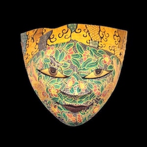 以下が含まれることがあります： 緑、黄色、赤の花柄が施されたカラフルな木製のマスク。マスクは笑顔で、大きな目と細かい花柄が特徴です。