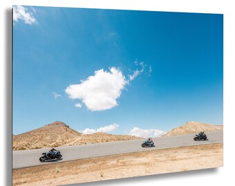 Des courses de motos sur une piste du désert en Californie avec un ciel bleu et des montagnes capturées lors d'une course de Superbike