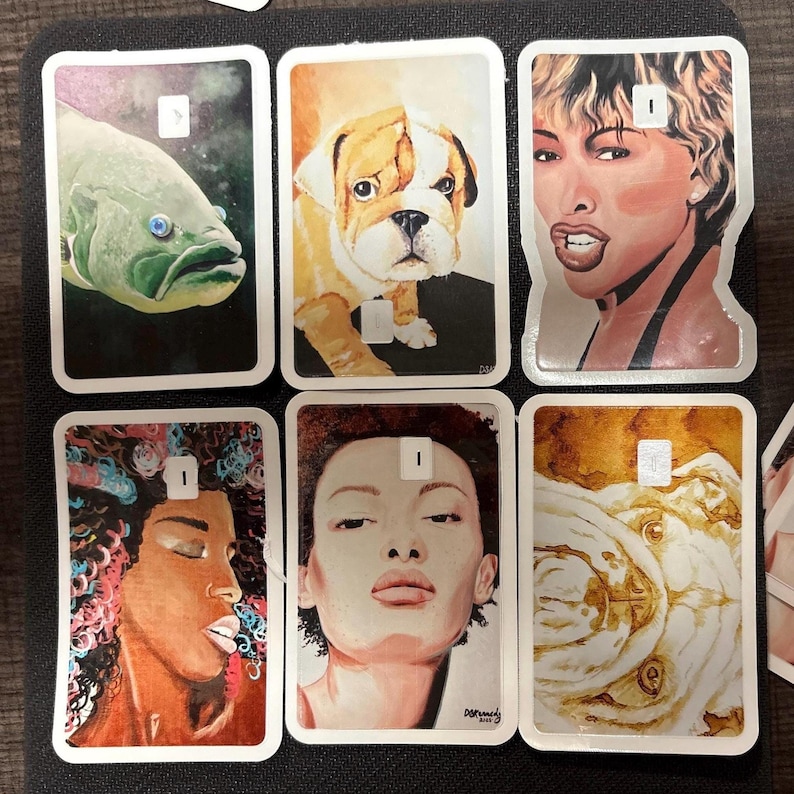 May include: A collection of six rectangular art cards featuring various portraits and illustrations. The cards depict a fish, a bulldog, a woman, and other portraits. Each card has a white border and a small white square at the top.