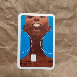 May include: A sticker featuring an illustration of a person with dark skin and a shaved head, set against a vibrant blue background. The artwork includes white lines suggesting headphones and a small white square. The sticker has a white border.