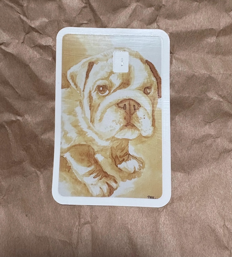 May include: A rectangular card featuring a watercolor painting of a bulldog puppy. The puppy has a light brown coat with darker brown markings and a sweet expression. The card has rounded corners and a white border.
