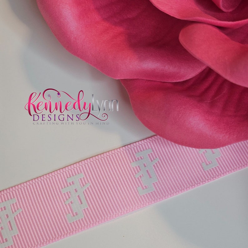 K&ouml;nnte beinhalten: Rosafarbenes Satinband mit wei&szlig;er Pr&auml;gung, auf dem "Kennedy Lynn Designs Crafting with you in mind" steht.