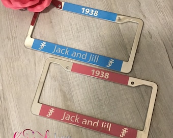 May include: Two silver license plate frames with blue and red inserts. The top frame has a blue insert with the text "1938" and "Jack and Jill". The bottom frame has a red insert with the text "1938" and "Jack and Jill".