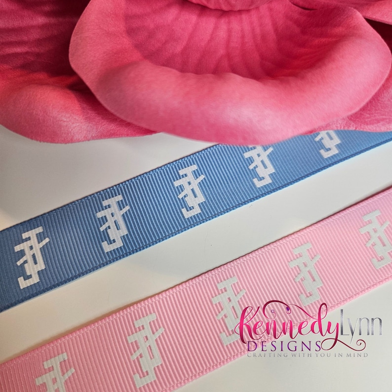 K&ouml;nnte beinhalten: Zwei Rollen Band mit einem sich wiederholenden wei&szlig;en Muster auf hellblauem und rosa Hintergrund. Das Band ist zum Basteln gedacht und tr&auml;gt den Text "Kennedy Lynn Designs Crafting with you in mind" auf dem rosa Band.