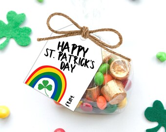 May include: A white gift tag with a rainbow and shamrock design. The tag reads "Happy St. Patrick's Day" and "From:". The tag is tied to a clear plastic bag filled with colorful candies.