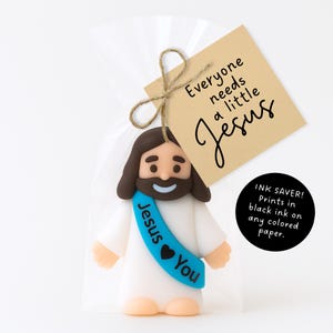 May include: A figurine of Jesus in a clear bag with a brown tag tied with twine. The tag reads "Everyone needs a little Jesus." The figurine has a blue sash that says "Jesus You."