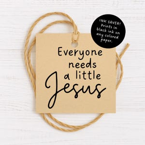 May include: A square, tan paper tag with the text "Everyone needs a little Jesus" in black script. A black circle with white text reads "INK SAVER! Prints in black ink on any colored paper." The tag is tied with a natural twine.