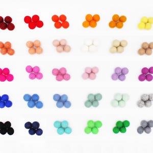 May include: A collection of thirty sets of four small, round felt balls arranged in a grid. Each set features a different solid color, including shades of red, orange, yellow, pink, blue, green, purple, brown, gray, black, and white.
