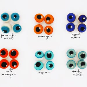 Peut inclure: Six ensembles de quatre yeux en laine feutr&eacute;e ronde de diff&eacute;rentes couleurs, chacun avec une pupille noire et un reflet blanc. Les couleurs incluent peacock mint, orange, royal blue, hot orange, aqua et dark mint, avec des &eacute;tiquettes.