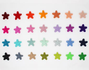May include: A collection of twenty-eight small, five-pointed star shapes made of felt, arranged in a grid of four rows and seven columns. The stars display a wide spectrum of colors, including various shades of red, orange, yellow, green, blue, purple, pink, brown, gray, and black.
