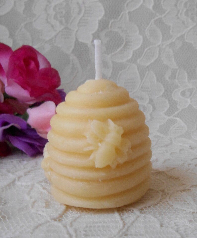 K&ouml;nnte beinhalten: Eine kleine, gelbe Bienenwachskerze in Form einer Honigwabe mit einem wei&szlig;en Docht. Die Kerze hat ein Bienenmotiv auf der Vorderseite.