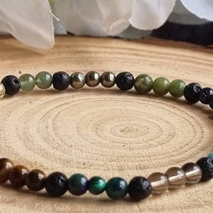 Op de afbeelding: Een kralenarmband met een verscheidenheid aan kleurrijke edelstenen en lavastenen. De armband bevat amethist, citrien, turquoise en andere stenen. De kralen zijn geregen op een elastisch koord. De armband wordt gepresenteerd op een houten oppervlak.