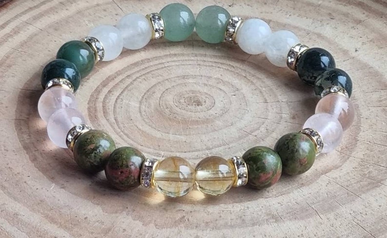 May include: A bracelet made of various gemstones, including green aventurine, white moonstone, rose quartz, and citrine. The bracelet is accented with gold-toned beads and clear crystals.