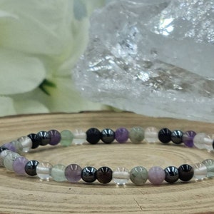 Puede incluir: Un brazalete hecho de cuentas de amatista, cuarzo transparente, fluorita verde y hematites.
