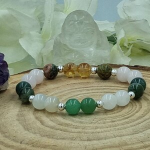 May include: A bracelet made with various semi-precious stones, including green aventurine, rose quartz, clear quartz, and tiger's eye. The bracelet is strung on a silver chain.