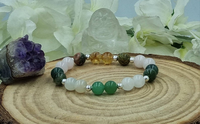 May include: A bracelet made with various semi-precious stones, including green aventurine, rose quartz, clear quartz, and tiger's eye. The bracelet is strung on a silver chain.