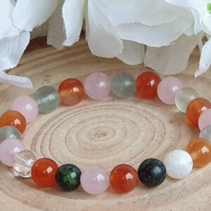 May include: A bracelet made of various semi-precious stones, including green aventurine, carnelian, rose quartz, clear quartz, and black obsidian. The bracelet is strung on elastic cord and is approximately 7 inches in length.