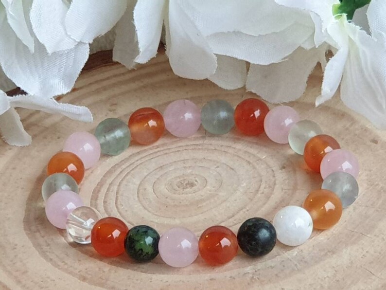 May include: A bracelet made of various semi-precious stones, including green aventurine, carnelian, rose quartz, clear quartz, and black obsidian. The bracelet is strung on elastic cord and is approximately 7 inches in length.