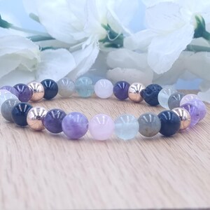 Könnte beinhalten: Ein Armband aus verschiedenen farbigenen Edelsteinperlen, darunter Amethyst, Rosenquarz, Fluorit, Labradorit und schwarzer Onyx. Das Armband hat außerdem roségoldene Abstandshalter.