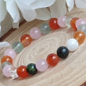 May include: A bracelet made of various semi-precious stones, including pink, green, white, and orange beads.