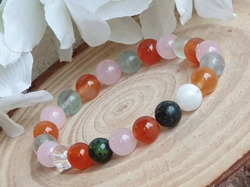 May include: A bracelet made of various semi-precious stones, including pink, green, white, and orange beads.