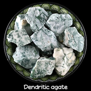Puede incluir: Un cuenco de piedras de ágata dendrítica en bruto, rugosas, blancas y verdes. Las piedras tienen un aspecto natural y terroso.