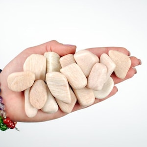 May include: A collection of smooth, light pink and white tumbled stones. The stones are various shapes and sizes, and have a slightly rough texture.