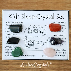 May include: A Kids Sleep Crystal Set on a white card. The set includes Blue Tiger Eye, Obsidian, Aventurine, Red Jasper, Amethyst, and Rose Quartz crystals. The card has illustrations and text describing each crystal's properties.
