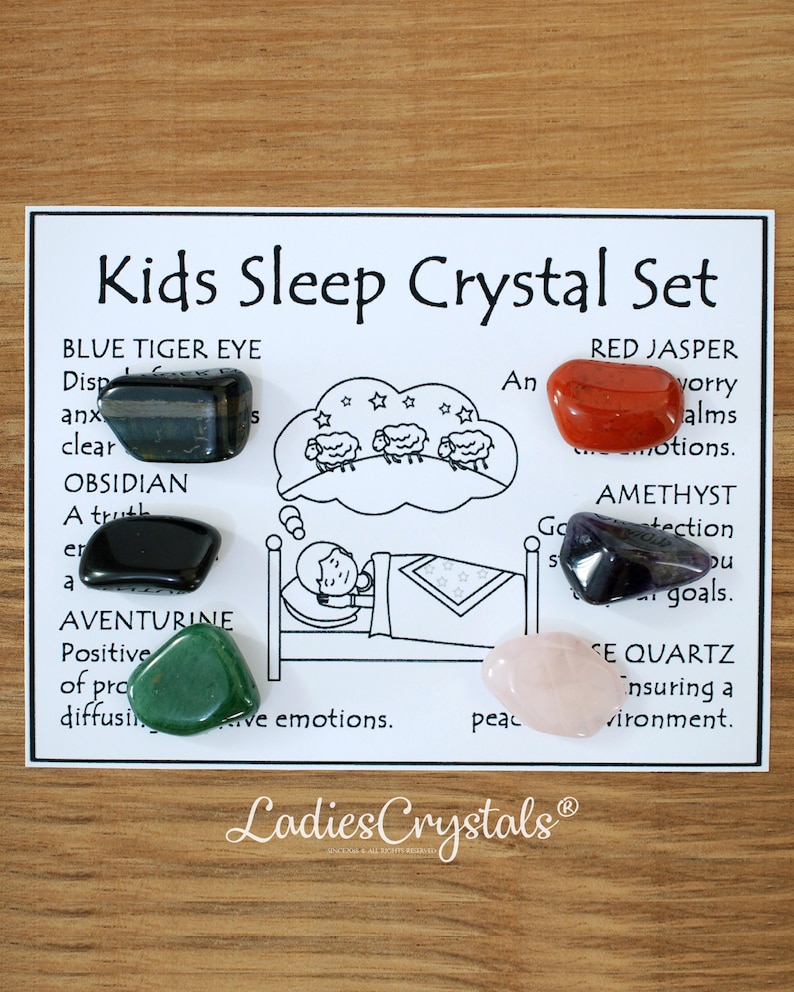 May include: A Kids Sleep Crystal Set on a white card. The set includes Blue Tiger Eye, Obsidian, Aventurine, Red Jasper, Amethyst, and Rose Quartz crystals. The card has illustrations and text describing each crystal's properties.