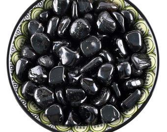 May include: A bowl filled with black tourmaline tumbled stones. The bowl has a green and white patterned design.