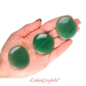 Peut inclure: Trois pierres lisses de jade vert, également connues sous le nom d'aventurine, dans la paume d'une main. Les pierres sont rondes et polies.
