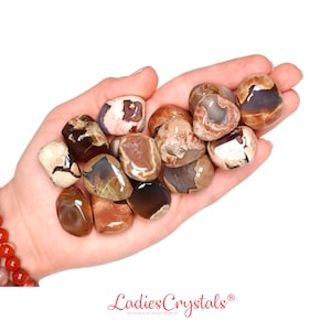 Puede incluir: Una colección de piedras de ágata pulidas de color marrón, blanco y gris con una variedad de patrones y texturas. Las piedras son lisas y pulidas, y están dispuestas en una mano.