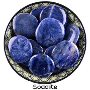 Puede incluir: Un cuenco de piedras de sodalita lisas y pulidas. Las piedras son de un azul profundo con vetas blancas y est&aacute;n dispuestas en un patr&oacute;n circular. El cuenco est&aacute; decorado con un patr&oacute;n verde y blanco.