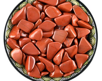 May include: A bowl filled with red jasper tumbled stones. The stones are a deep red color with white veins running through them. The bowl is decorated with a yellow and green pattern.