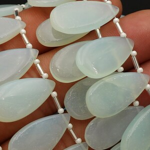 Peut inclure: Un brin de perles de pierres précieuses vert clair en forme de larme. Les perles sont enfilées sur un fil d'argent avec de petites perles d'argent entre chaque pierre précieuse.