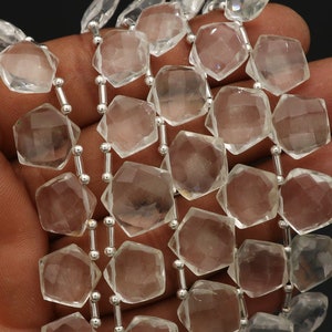 Op de afbeelding: Een streng van heldere, gefacetteerde, vijfhoekige kwartskralen, geregen met kleine zilverkleurige metalen tussenkralen. De transparante stenen hebben meerdere geometrische facetten die het licht reflecteren voor een sprankelend effect.