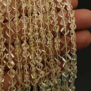 May include: Strands of faceted, light yellow gemstone beads. The beads are diamond-shaped and strung together with a thin, light-colored cord. The gemstones have a translucent quality, and the overall effect is delicate and elegant.