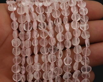 May include: Strands of pale pink rose quartz beads. The beads are oval-shaped and strung together with a thin, pale pink string. The beads have a translucent quality and a polished finish. The background is a dark colour.
