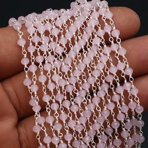 Könnte beinhalten: Nahaufnahme einer Kette aus zarten, rosafarbenen Edelsteinperlen, aufgereiht auf einer Silberkette. Die kleinen, facettierten Perlen sind gleichmäßig angeordnet und erzeugen einen schimmernden Effekt. Die Kette ist zwischen den Perlen sichtbar.