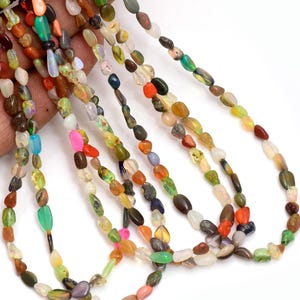Peut inclure: Plusieurs brins de perles de pierres précieuses multicolores de différentes formes et tailles. Les perles sont un mélange de couleurs, notamment vert, orange, jaune et marron. Les perles sont enfilées, pour un collier ou un bracelet.