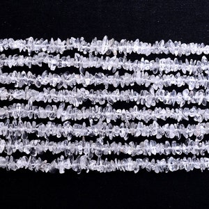 Op de afbeelding: Een streng met heldere kwarts chips. De kralen zijn klein en onregelmatig van vorm en zijn aan elkaar geregen op een heldere draad. De kralen zijn in een rechte lijn gerangschikt en zijn allemaal even groot.
